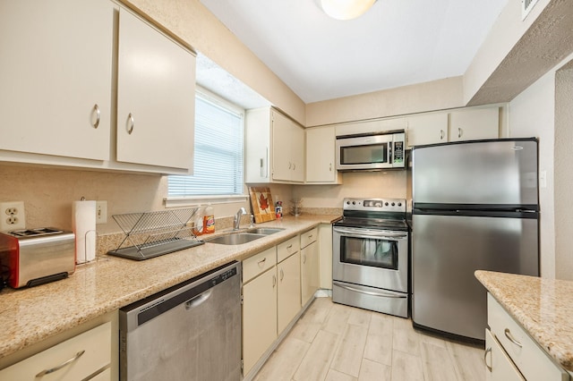 kitchen with light stone countertops, sink, and stainless steel appliances