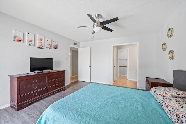 bedroom with light wood-type flooring, ceiling fan, and a textured ceiling