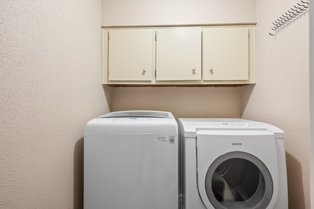 washroom featuring cabinets and separate washer and dryer