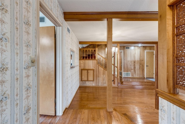 corridor with light wood-type flooring and a textured ceiling