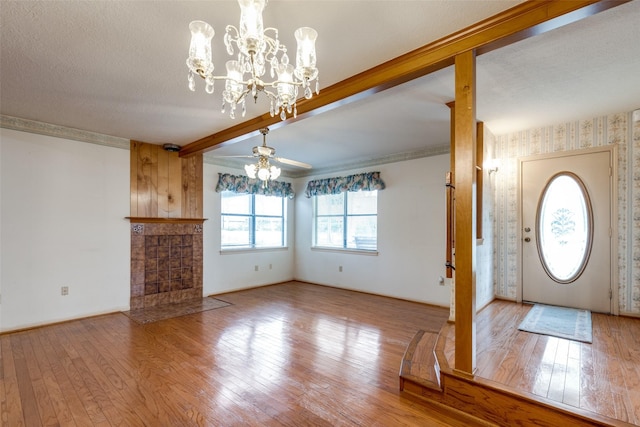 unfurnished living room with light hardwood / wood-style floors, a textured ceiling, beamed ceiling, and ceiling fan with notable chandelier