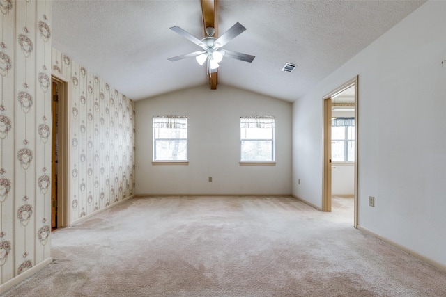 carpeted empty room with ceiling fan, a textured ceiling, and vaulted ceiling with beams