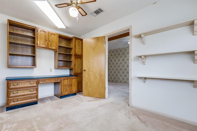 unfurnished office featuring light carpet, ceiling fan, built in desk, and lofted ceiling