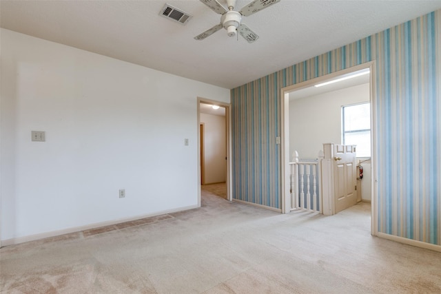 spare room with ceiling fan and light colored carpet