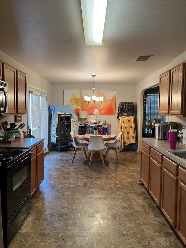 kitchen featuring a textured ceiling, black / electric stove, sink, hanging light fixtures, and a notable chandelier