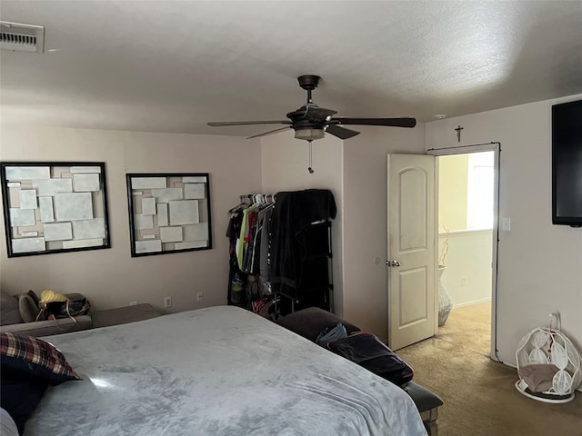 carpeted bedroom featuring ceiling fan and a textured ceiling