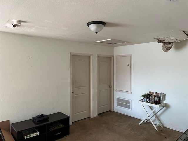 interior space featuring dark carpet and a textured ceiling