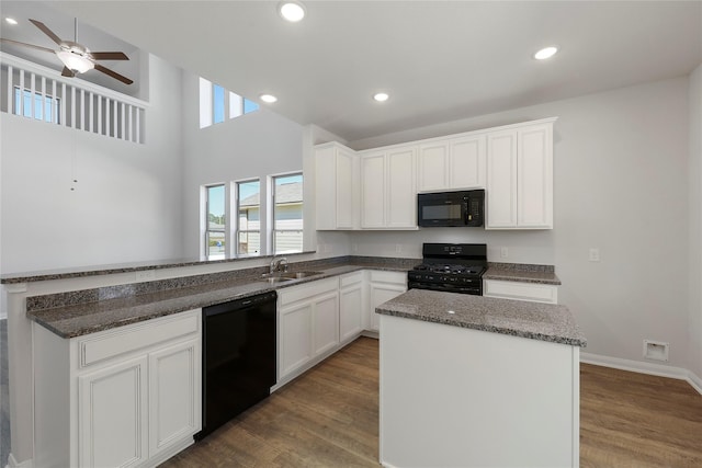 kitchen featuring black appliances, white cabinets, sink, and a center island