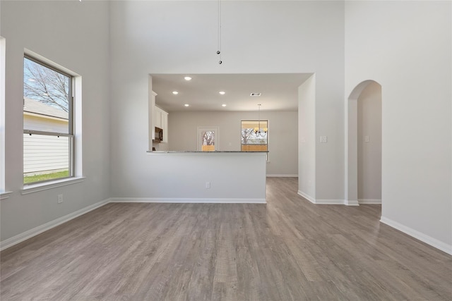 unfurnished living room with light hardwood / wood-style floors and a towering ceiling