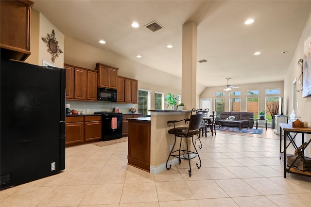 kitchen featuring black appliances, a healthy amount of sunlight, a kitchen bar, and ceiling fan