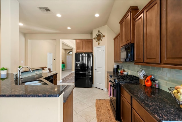 kitchen with light tile patterned floors, tasteful backsplash, dark stone countertops, black appliances, and sink