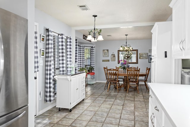 kitchen featuring white cabinetry, pendant lighting, stainless steel fridge, and a notable chandelier