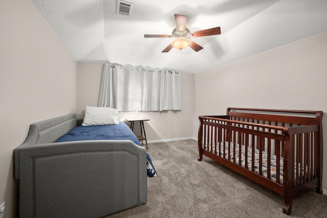 bedroom featuring ceiling fan, vaulted ceiling, carpet, and a crib