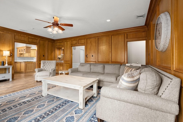 living room with ceiling fan, ornamental molding, and light hardwood / wood-style floors