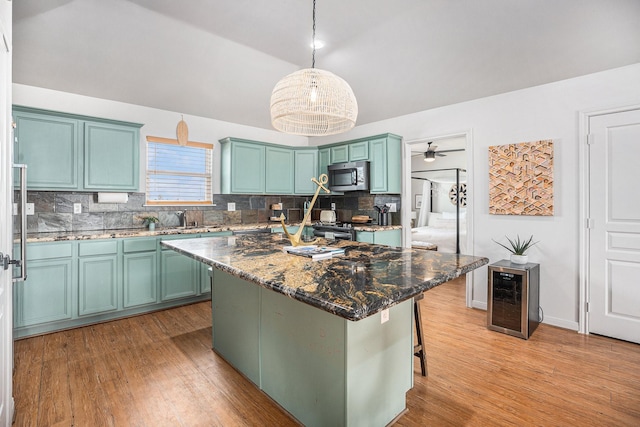 kitchen featuring stainless steel appliances, decorative light fixtures, wine cooler, dark stone counters, and a center island