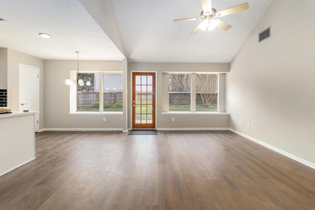 unfurnished living room featuring vaulted ceiling, dark hardwood / wood-style flooring, and ceiling fan with notable chandelier