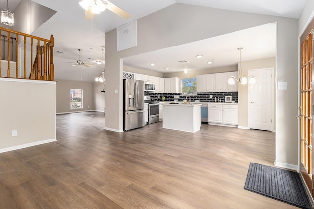 kitchen featuring decorative backsplash, white cabinetry, appliances with stainless steel finishes, and pendant lighting