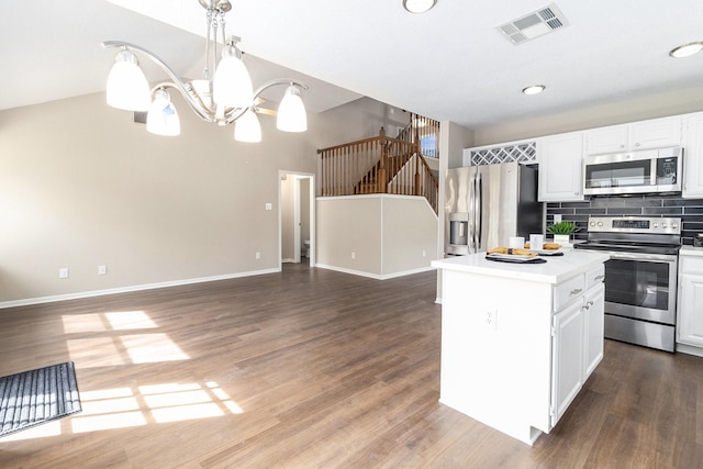 kitchen featuring white cabinetry, appliances with stainless steel finishes, tasteful backsplash, decorative light fixtures, and a center island