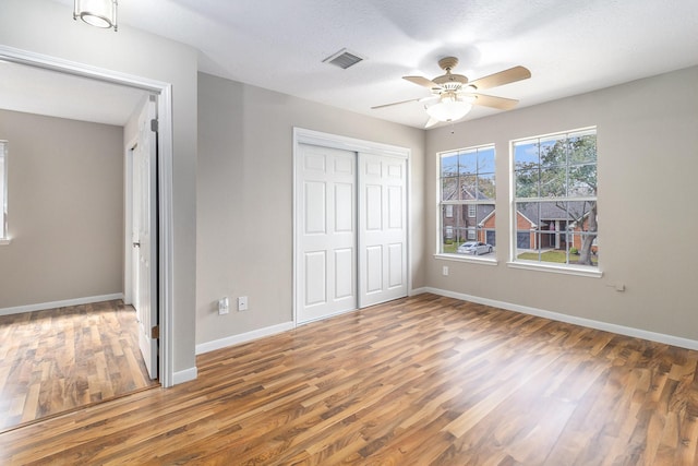 unfurnished bedroom with ceiling fan, a closet, and dark wood-type flooring