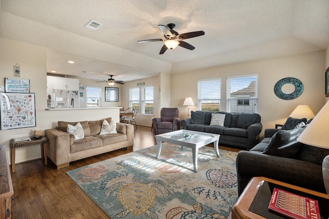 living room with a textured ceiling, ceiling fan, dark hardwood / wood-style flooring, and a tray ceiling