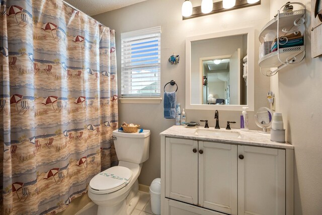 bathroom featuring toilet, tile patterned flooring, walk in shower, a textured ceiling, and vanity