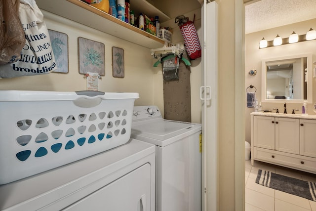 laundry room featuring laundry area, a textured ceiling, separate washer and dryer, a sink, and light tile patterned flooring