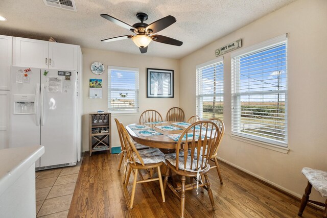 dining space with ceiling fan, light wood-type flooring, and a textured ceiling