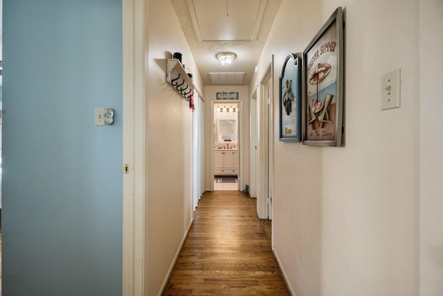 corridor with a textured ceiling and hardwood / wood-style floors