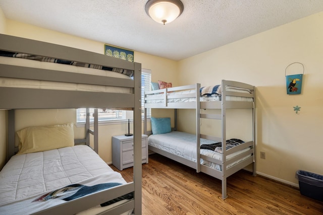 bedroom featuring a textured ceiling, baseboards, and wood finished floors