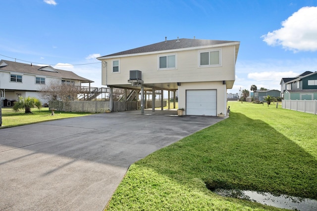 rear view of property with a garage, central air condition unit, a lawn, and a carport