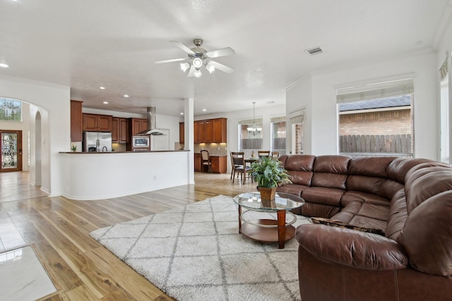 living room with ceiling fan, plenty of natural light, light hardwood / wood-style flooring, and ornamental molding