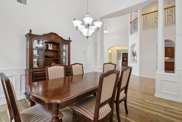 dining space with a notable chandelier, a towering ceiling, and hardwood / wood-style floors