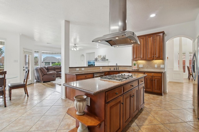 kitchen with ceiling fan, a kitchen island, island exhaust hood, light tile patterned flooring, and appliances with stainless steel finishes