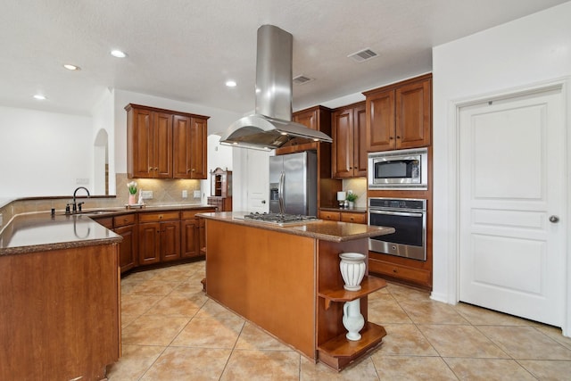 kitchen featuring kitchen peninsula, island exhaust hood, appliances with stainless steel finishes, decorative backsplash, and a center island