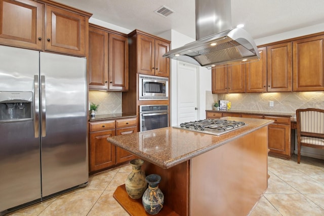 kitchen with a kitchen island, light stone countertops, stainless steel appliances, light tile patterned floors, and island range hood