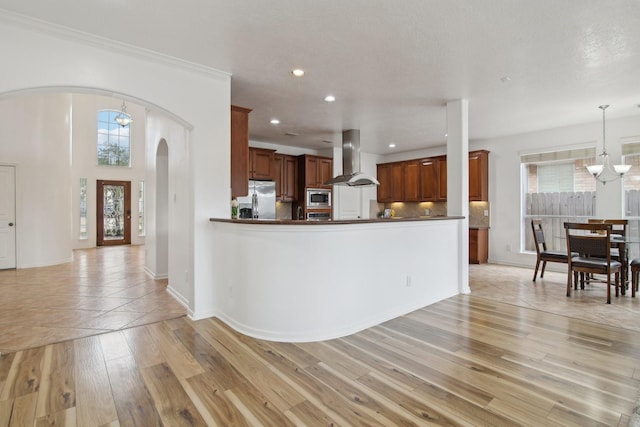 kitchen featuring decorative light fixtures, kitchen peninsula, island exhaust hood, an inviting chandelier, and stainless steel appliances