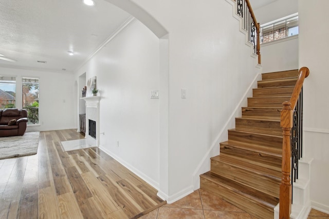 stairway with wood-type flooring and crown molding