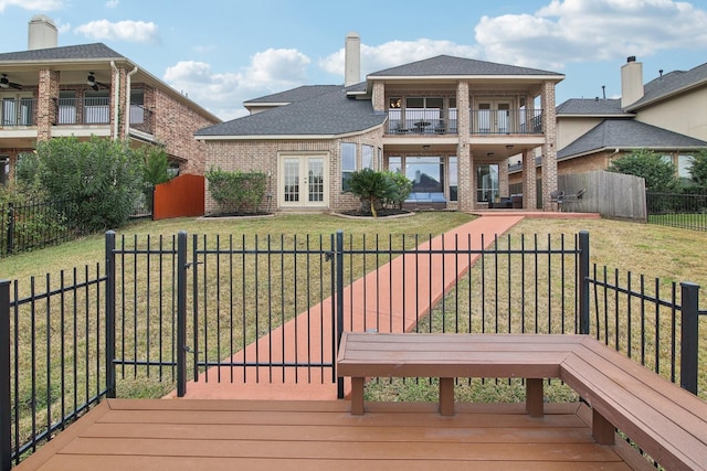 back of house featuring a lawn, french doors, and a balcony