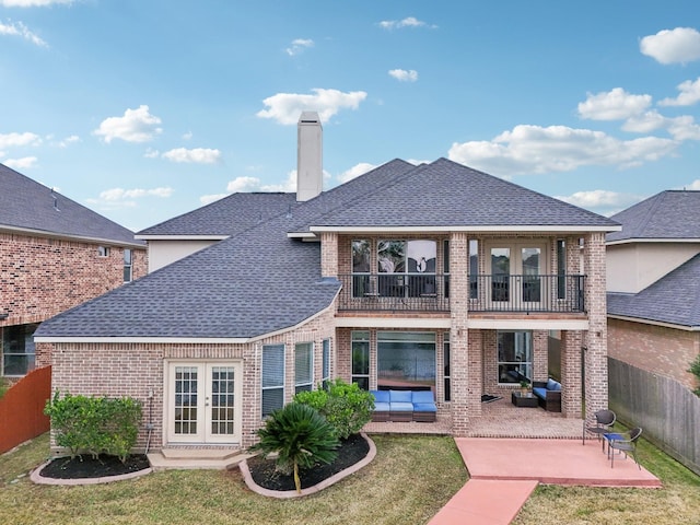 rear view of property with a patio area, outdoor lounge area, a lawn, a balcony, and french doors