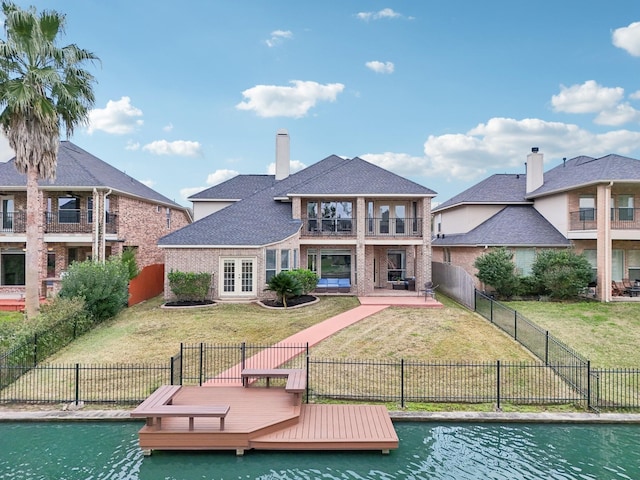 back of property featuring a water view, french doors, a lawn, and a balcony