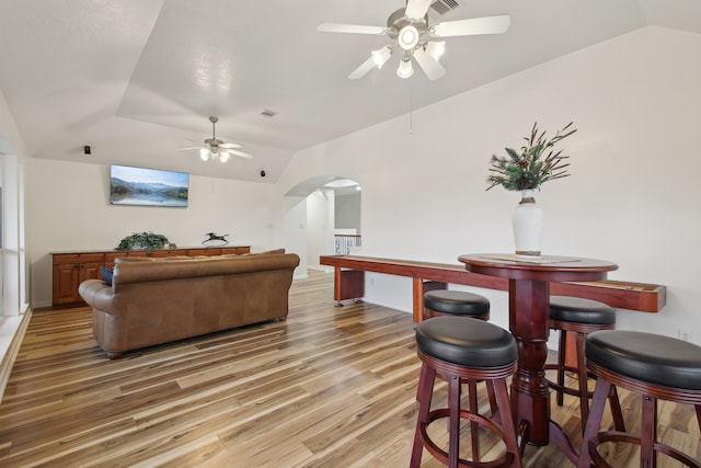 living room featuring ceiling fan, hardwood / wood-style floors, and vaulted ceiling