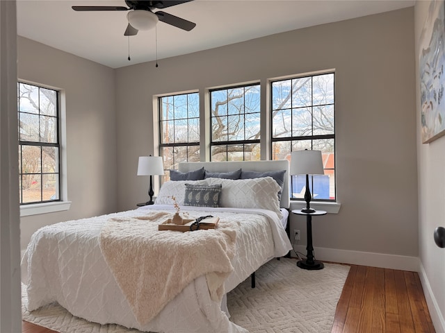 bedroom featuring ceiling fan, multiple windows, and wood-type flooring