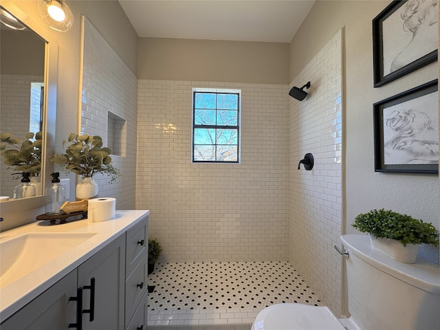 bathroom featuring toilet, vanity, tile patterned flooring, and tiled shower