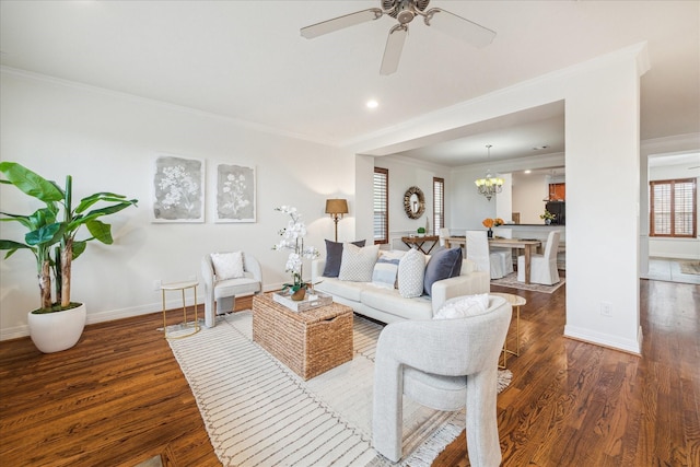 living room with dark wood-type flooring, ceiling fan with notable chandelier, and ornamental molding