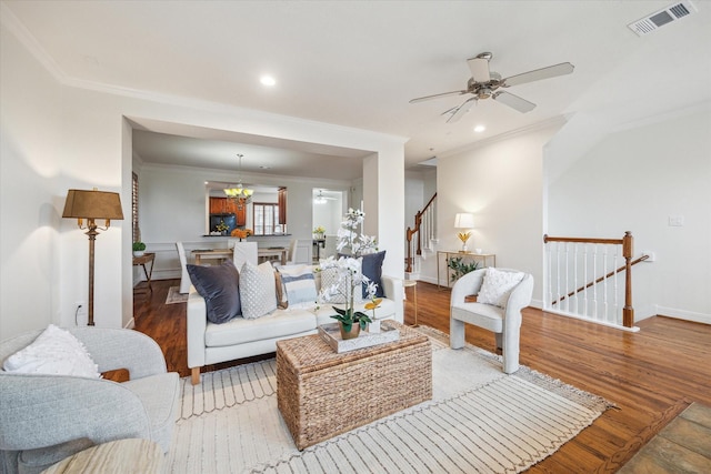 living room featuring ceiling fan with notable chandelier, crown molding, and light wood-type flooring