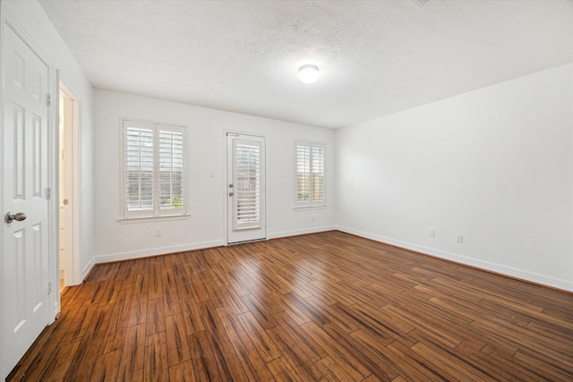 empty room featuring dark hardwood / wood-style floors, plenty of natural light, and a textured ceiling