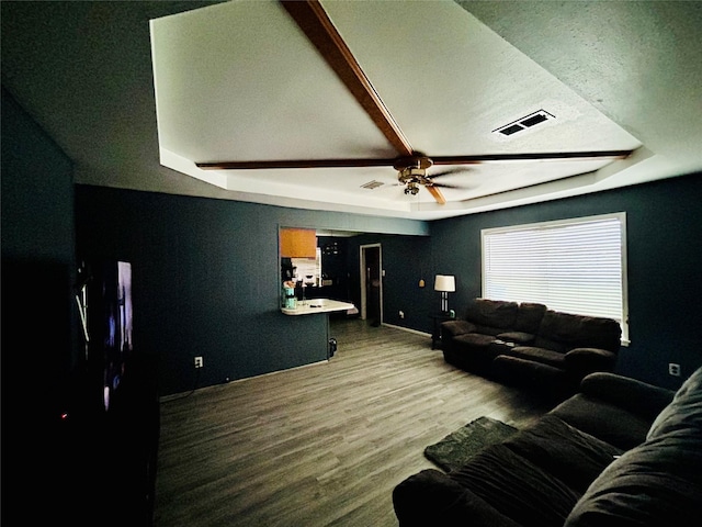 living room with a raised ceiling, ceiling fan, and wood-type flooring