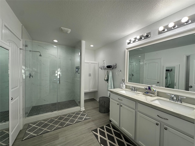 bathroom with a shower with shower door, vanity, a textured ceiling, and hardwood / wood-style floors