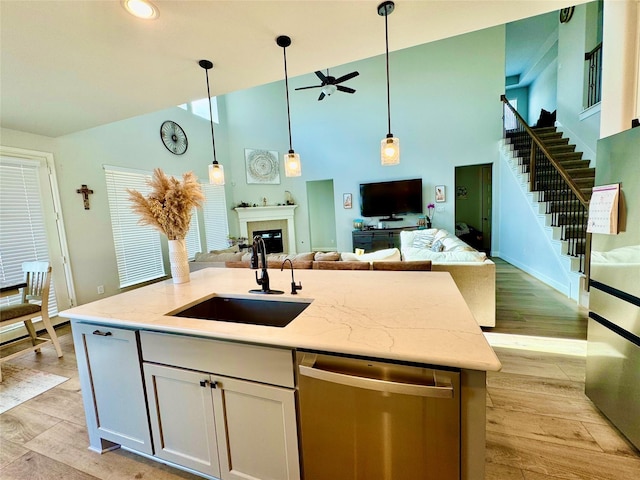 kitchen with sink, white cabinetry, light hardwood / wood-style flooring, appliances with stainless steel finishes, and an island with sink