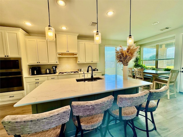 kitchen with appliances with stainless steel finishes, sink, white cabinetry, and pendant lighting